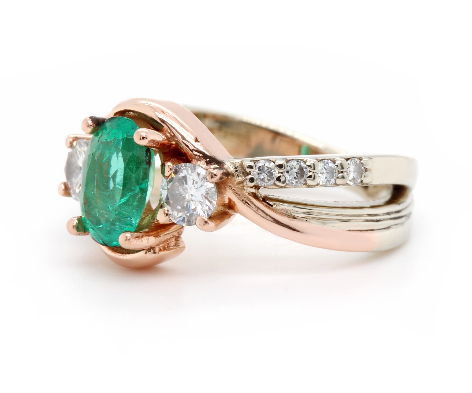 Anillo de oro rosa curvado con diamantes y tres piedras esmeralda