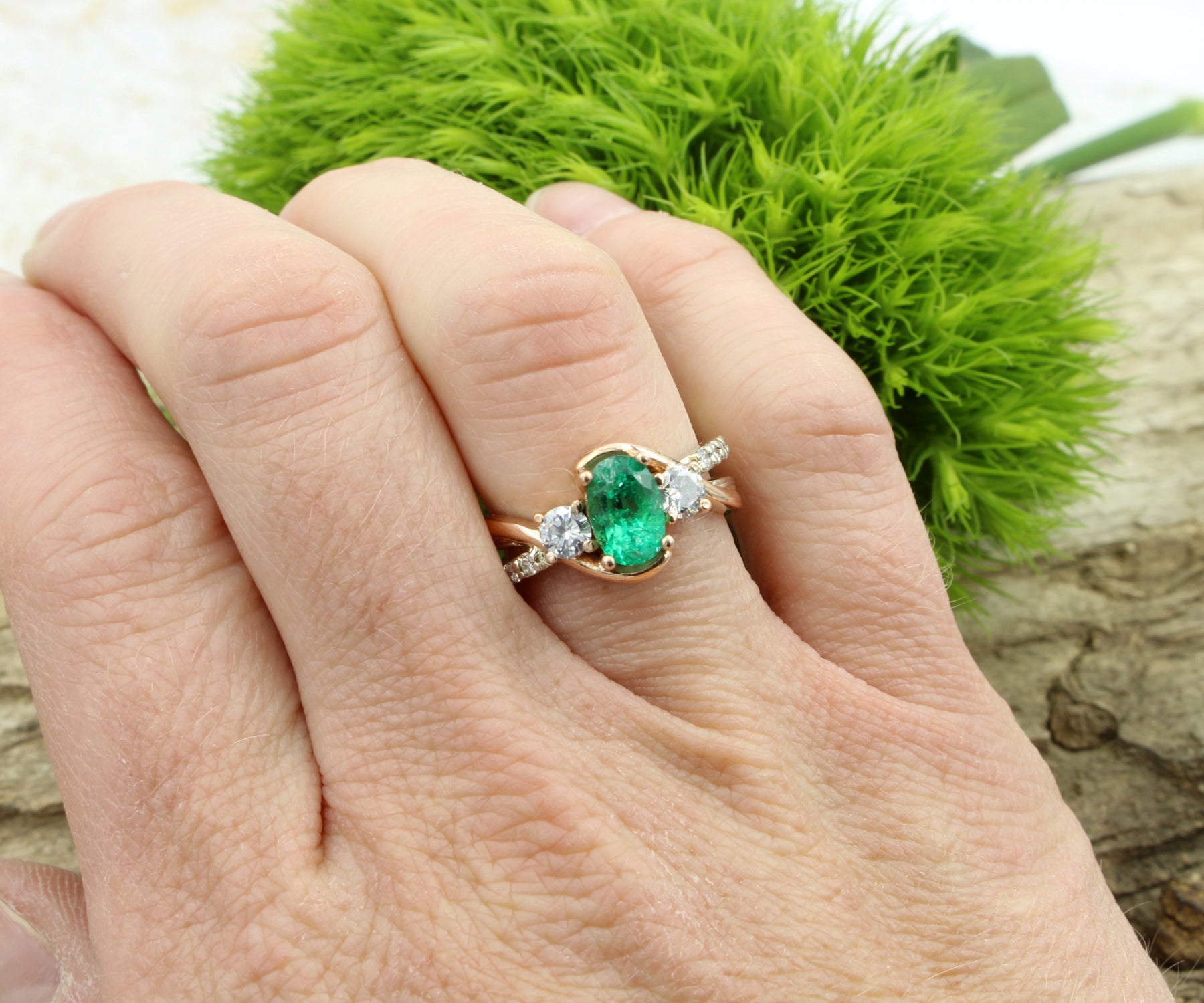Anillo de oro rosa curvado con diamantes y tres piedras esmeralda