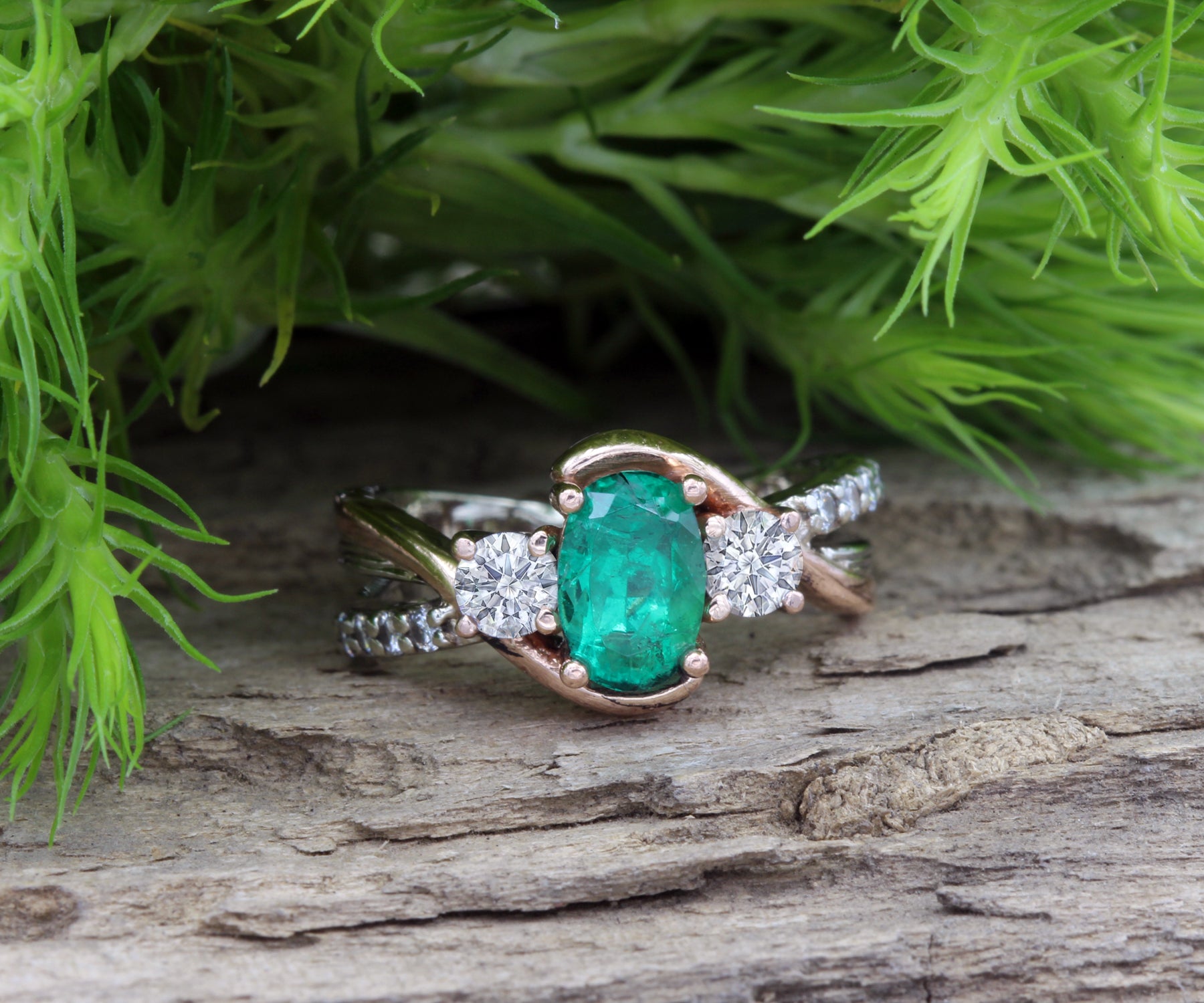 Anillo de oro rosa curvado con diamantes y tres piedras esmeralda